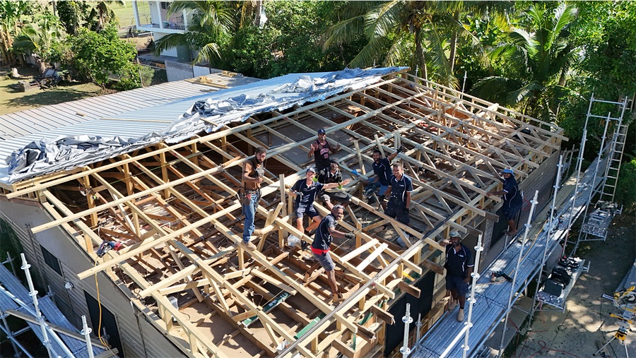 A coordinated crew installing a full roof structure, seen from above