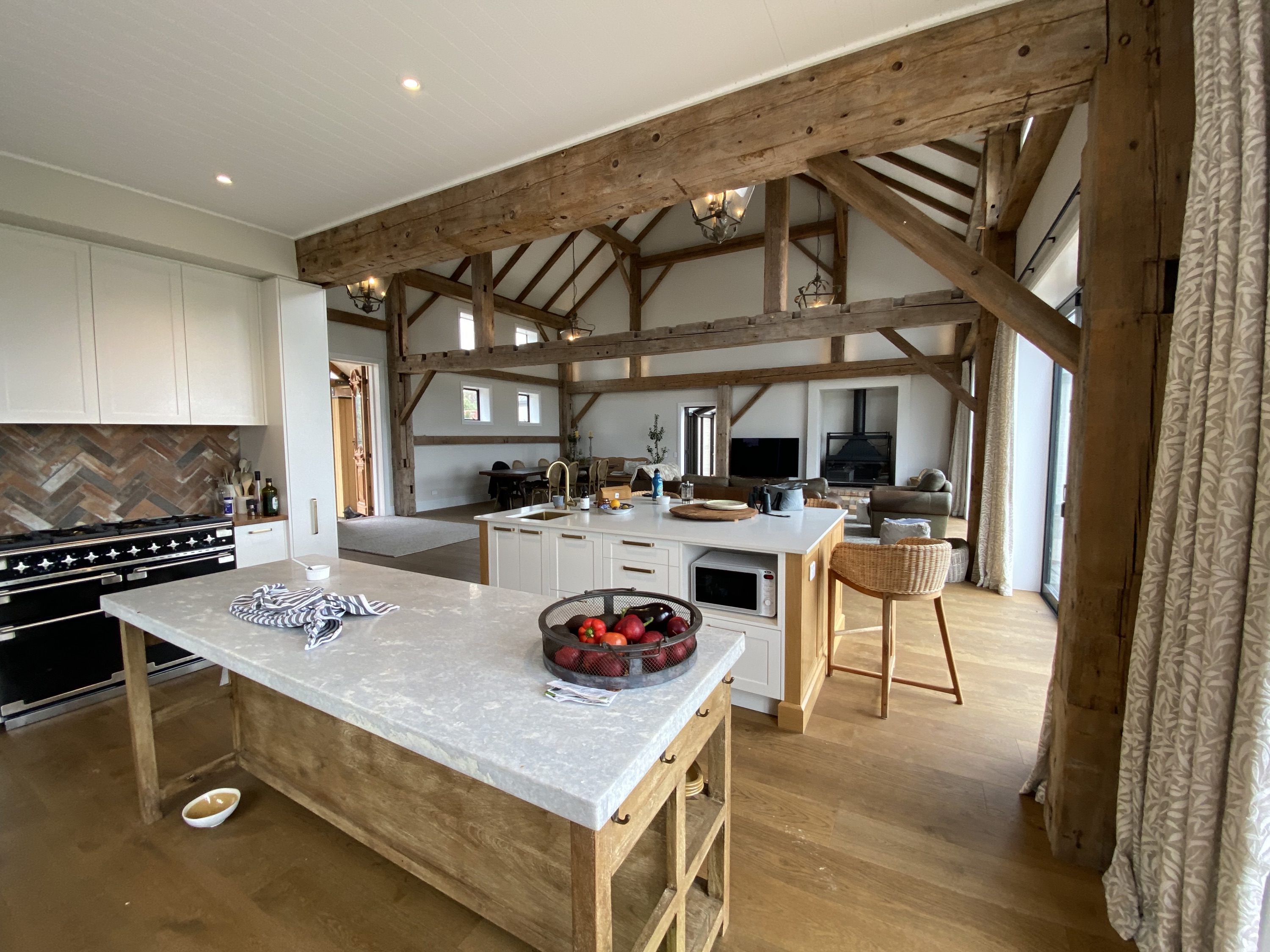 Kitchen with marble island beneath reclaimed timber beams